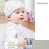 A baby wearing a knitted hat and vest, sitting indoors. Produktbild-Vorschau