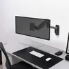 A monitor arm mounted on a wall above a desk. Podgląd zdjęcia produktu