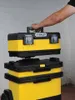 A person's arm is shown lifting a yellow and black Stanley toolbox from a stack of toolboxes. Voir les images du produit