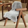 A gray faux fur rug draped over a wooden chair next to a wooden table. Náhled obrázku produktu