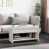 A white coffee table is placed in front of a sofa in a living room setting. A laptop, a cup, and a small plant are on top of the table. Books and decorative items are on the shelf below. Voir les images du produit