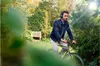 A man is riding a bicycle in a park while wearing headphones. Voir les images du produit