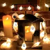 Halloween ghost string lights are draped around a rustic lantern and near a large pillar candle. Produktbild-Vorschau