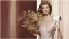 A woman is holding a white hair dryer and her long blonde hair is blowing in the wind. Náhled obrázku produktu