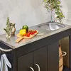 An outdoor kitchen setup with a sink, countertop, and storage cabinets, featuring fresh vegetables on a cutting board. Anteprima dell’immagine prodotto