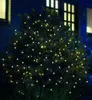 A bush decorated with warm white LED lights at night, with a house in the background. Produktbild-Vorschau