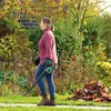 A woman is using a leaf blower in a garden during autumn. Produktbild-Vorschau