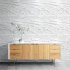 A white 3D wall paneling is shown behind a wooden sideboard with a plant on top. Produktbild-Vorschau
