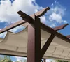 Close-up view of a wooden pergola with a beige canopy against a blue sky with clouds. Podgląd zdjęcia produktu