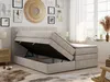 A bedroom scene with a beige boxspring bed with its storage compartment open, showcasing the interior. The room is decorated with artwork and has natural light coming from a window. Produktbild-Vorschau