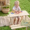 A young child playing with magnetic shapes on a wooden picnic table outdoors. Náhled obrázku produktu