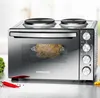 A countertop oven with a rotisserie chicken inside, placed on a kitchen counter with some vegetables and chili peppers nearby. Produktbild-Vorschau