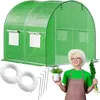 A woman holding plants and a small potted plant in front of a green greenhouse. Produktbild-Vorschau
