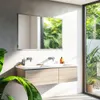 A modern bathroom with a double vanity, mirror, and large window overlooking lush greenery. Produktbild-Vorschau