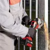 A person is using an angle grinder to cut a metal fence, creating sparks. Podgląd zdjęcia produktu