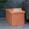 An orange fabric storage ottoman sits on a tiled floor next to a dark gray sofa and a plant. Two books are stacked on top of the ottoman. Anteprima dell’immagine prodotto