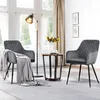 Two gray upholstered chairs with a throw blanket on one, a small side table with a vase of sunflowers, and a floor lamp in a well-lit room with sheer curtains. Produktbild-Vorschau