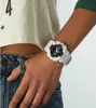 A person wearing a white Casio G-Shock watch on their wrist, with part of their torso and jeans visible. Produktbild-Vorschau