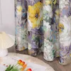 A close-up view of floral patterned curtains hanging in a room, with a lamp and a book on the floor. Produktbild-Vorschau
