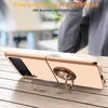 A person wearing a grey sweater is in the background, and a rose gold phone case with a ring holder is in the foreground, resting on a wooden table. Produktbild-Vorschau