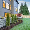 A backyard scene with a modern house, landscaping, and a wooden fence. Náhled obrázku produktu
