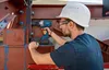 A construction worker using a cordless impact wrench on a large metal structure. Voir les images du produit