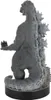 A grey Godzilla figurine is shown from the back, standing on a black circular base with a small city structure at its feet. Produktbild-Vorschau