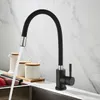 A black kitchen faucet with a flexible spout is shown in use, with water flowing into a sink. Several white ceramic containers with wooden lids are visible on the counter behind the faucet. Náhľad obrázku produktu