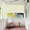 A balcony with a chair and a side table, featuring a beige roller blind. Náhled obrázku produktu