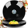 A stack of black plates with spaghetti on the top plate, surrounded by flying ingredients. Podgląd zdjęcia produktu