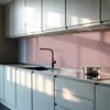 A modern kitchen with light gray cabinets and a pink backsplash. A black faucet is visible over a sink, and a pot sits on a stovetop. Podgląd zdjęcia produktu