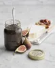 A jar of fig jam with figs and cheese on a marble surface. Voir les images du produit
