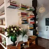 A room interior with shelves filled with books, a bouquet of flowers, and decorative items. Produktbild-Vorschau