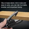 A hand is holding a black clip-on stand, which is attached to a wooden surface. Voir les images du produit