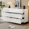 A white, high-gloss sideboard with six drawers is shown in a well-lit room with a plant and decorative items on top. Produktbild-Vorschau