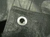 A close-up view of a black tarp with a metal grommet. Anteprima dell’immagine prodotto