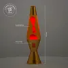 A lava lamp with red lava blobs inside, standing on a surface against a grey background. Anteprima dell’immagine prodotto