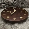 A wooden wall clock with gold numbers and a deer logo is placed on a textured, grey background. Voir les images du produit