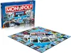A Monopoly board game box and its unfolded board are displayed on a white background. Produktbild-Vorschau