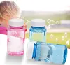 Drei kleine Plastikflaschen mit Seifenblasenlösung, eine rosa, zwei blau, mit weißen Verschlüssen, vor einem Kind, das Blasen bläst Náhled obrázku produktu