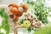Three stuffed animals, a monkey, a leopard, and a turtle, are arranged on a wooden shelf with ropes, surrounded by greenery. Produktbild-Vorschau