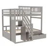 A gray wooden bunk bed with stairs and storage drawers, shown from a diagonal front-left angle against a white background. Náhled obrázku produktu