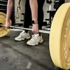 A person is lifting a barbell with weight plates in a gym. Produktbild-Vorschau