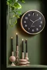 A wall clock and candles are displayed on a shelf against a green wall. Produktbild-Vorschau