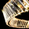 A close-up view of a gold-colored crystal chandelier or pendant light fixture against a black background. Produktbild-Vorschau