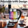 A glass electric kettle with colorful LED lighting is shown on a table, along with a cup and saucer, and a glass of amber liquid. Produktbild-Vorschau