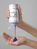 A hand holding a bottle of Olaplex No.5P Blonde Enhancer Toning Conditioner, with the conditioner being dispensed into the other hand. Náhled obrázku produktu