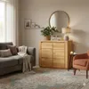 A living room scene featuring a wooden dresser, a sofa, an armchair, and a rug. Produktbild-Vorschau