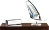 A silver speaker and a model windsurf sail are displayed on a dark wooden shelf against a white background. Náhled obrázku produktu