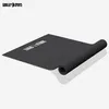 A black yoga mat is shown unrolled on a light gray surface with a white background. Produktbild-Vorschau